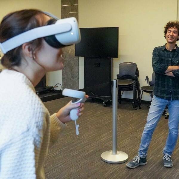 a student uses a VR headset while her professor looks on