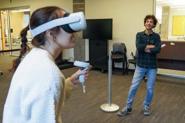 a student uses a VR headset while her professor looks on