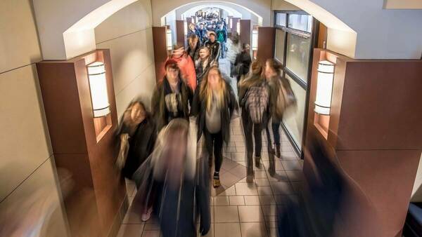 A busy DeBartolo Hall hallway full of students during a class change. The image is blurred, showing how quickly they're moving.