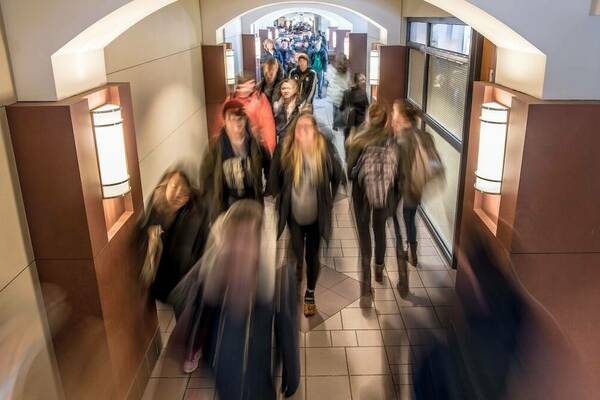 A busy DeBartolo Hall hallway full of students during a class change. The image is blurred, showing how quickly they're moving.