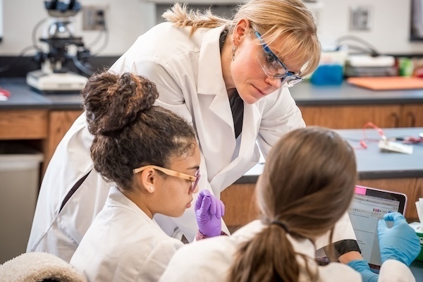 a professor (in safety glasses) works with two students during an undergraduate neuroscience class