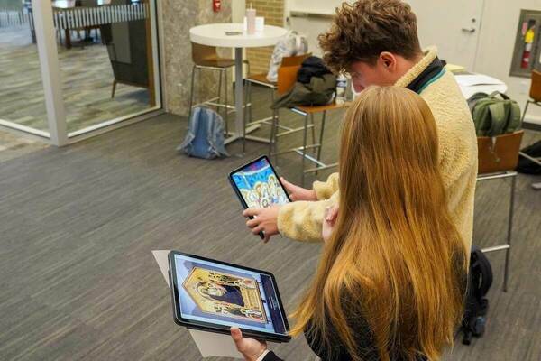 Two students in a Medieval-Renaissance Italian Literature and Culture course look at artwork on tablets in an augmented reality component of an XR experience.