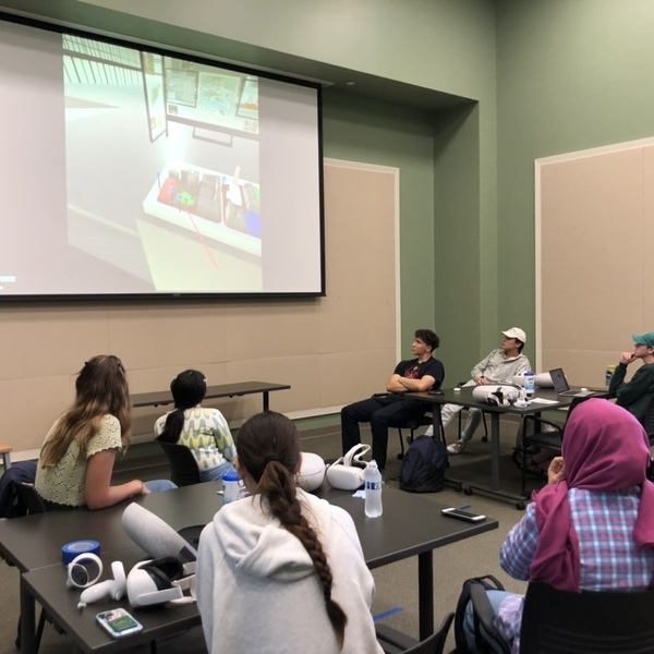 Students in a classroom watch a presentation that's been projected onto a screen.