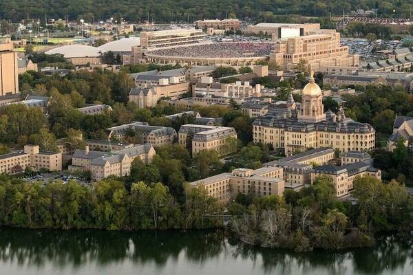 an aerial view of the Notre Dame campus looking to the southeast over Saint Mary's Lake, with the Golden Dome and other buildings in the foreground and Notre Dame Stadium in the distance in the background