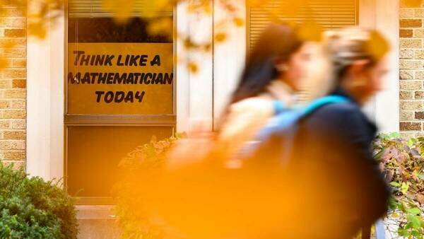 Two students walk by a “Think Like a Mathematician Today” sign in a Hayes-Healey window