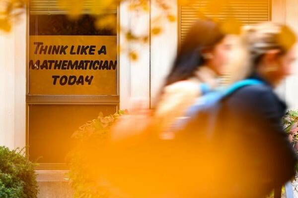 Two students walk by a “Think Like a Mathematician Today” sign in a Hayes-Healey window