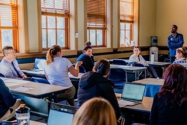 a woman makes a comment during a workshop while the presenter and other attendees listen