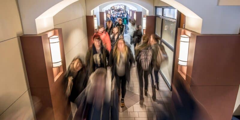 A busy DeBartolo Hall hallway full of students during a class change. The image is blurred, showing how quickly they're moving.